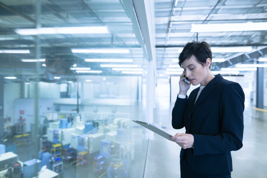 Geschäftsfrau am Telefon mit Blick auf eine Fabrik