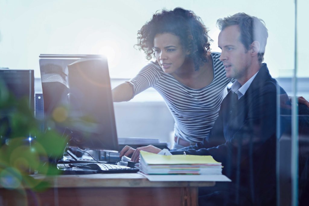 Zwei Personen schauen auf gemeinsamen Computerbildschirm